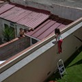 Gala, 7, speaks with her friend and classmate Oliver, 6, from a wall on their courtyard..jpg